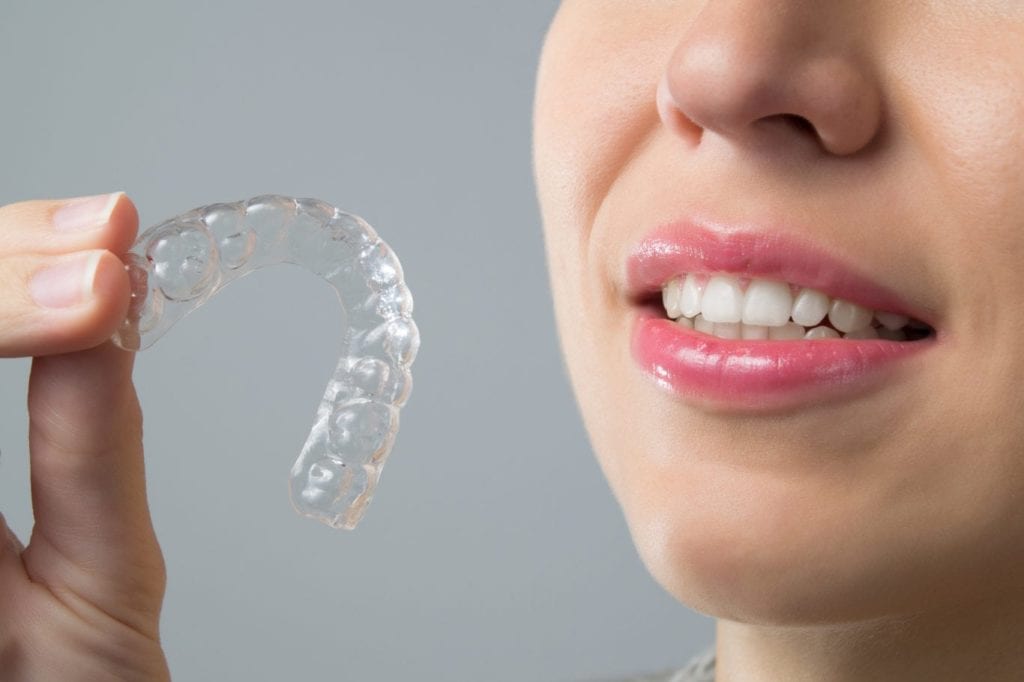 patient holding her Invisalign clear aligners